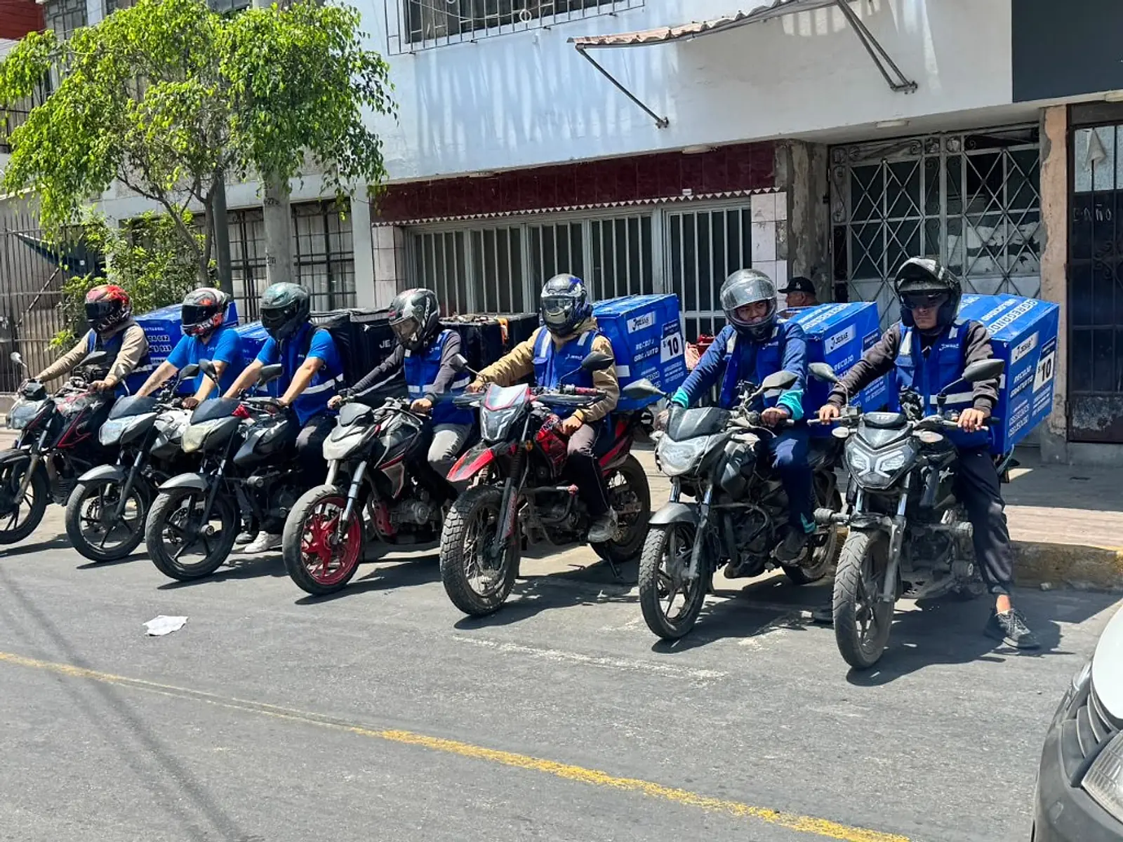 Equipo de motorizados JESAS Courier con sus cajas y chalecos azules